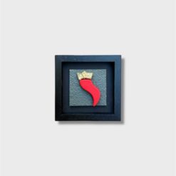 Quadro Corno Artigianale con Cornice Nera realizzato a mano secondo la tradizione mediterranea, con finiture materiche e dettagli a rilievo che esaltano il simbolo del corno in chiave contemporanea. La cornice esterna nera dona contrasto e profondità, rendendo l’opera elegante e facilmente integrabile in ambienti moderni e classici. Disponibile in diverse colorazioni del soggetto e del fondo, il quadro è progettato per essere sia appeso al muro sia appoggiato su mensole, mobili o camini, offrendo massima versatilità d’uso. Realizzato con materiali selezionati e imballato con cura per la spedizione, è ideale come elemento d’arredo distintivo o come regalo simbolico. Inserisci la variante colore desiderata e scegli la misura più adatta al tuo spazio per portare un tocco artigianale e mediterraneo nella tua casa.